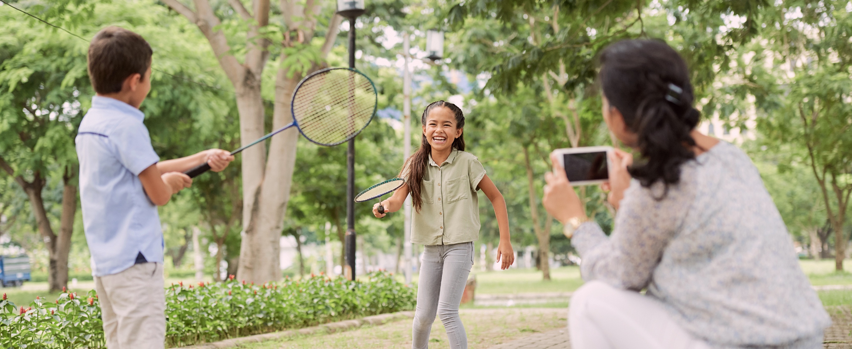 Mother takes a photo of her kids playing badminton